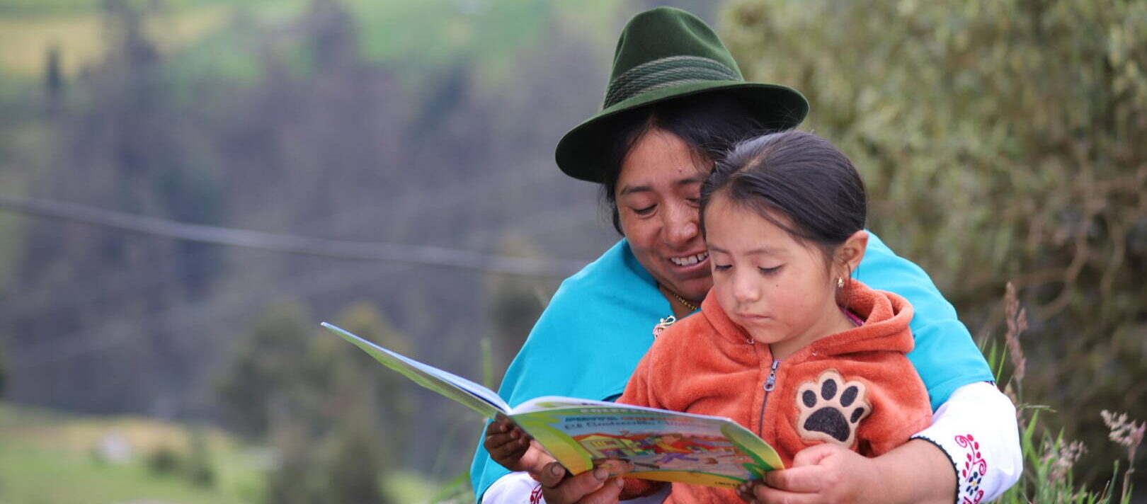María wraps her arms around her daughter, Dayana, while she reads to her.