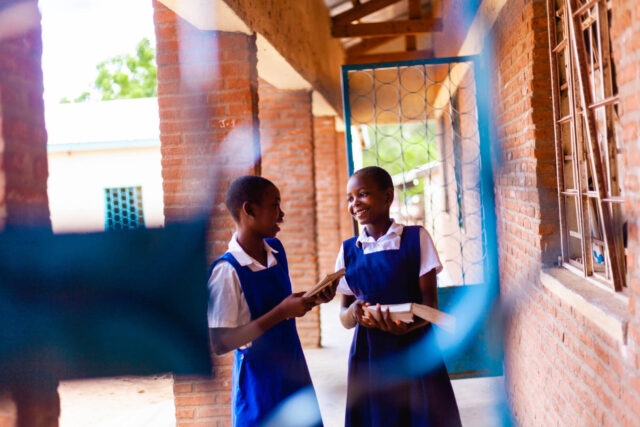Two Malawian girls in school uniforms can study safely thanks to World Vision’s work to reduce malaria in students.