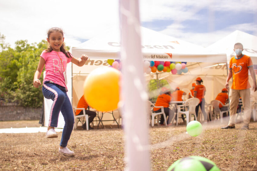 A Salvadoran girl who chose her own sponsor through World Vision kicks a yellow ball into a net.