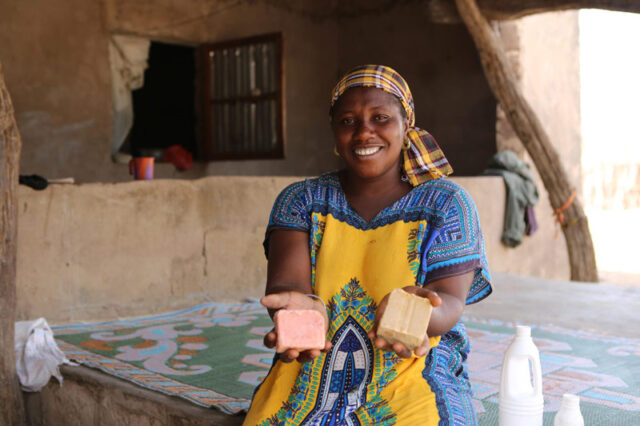 a Senegalese woman holding two soup blocks she makes