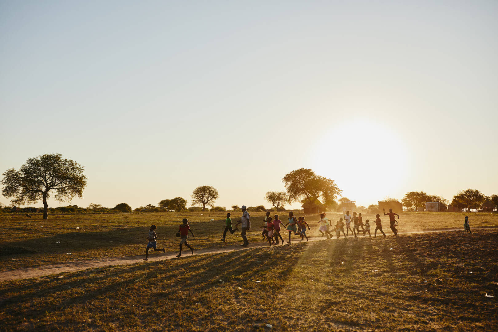 A group of children run in the light of a sunset