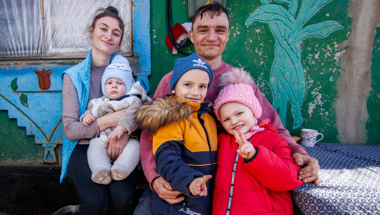 Ukrainian refugees in Moldova. Dressed in winter gear, the father embraces his two children while the mother holds a baby.