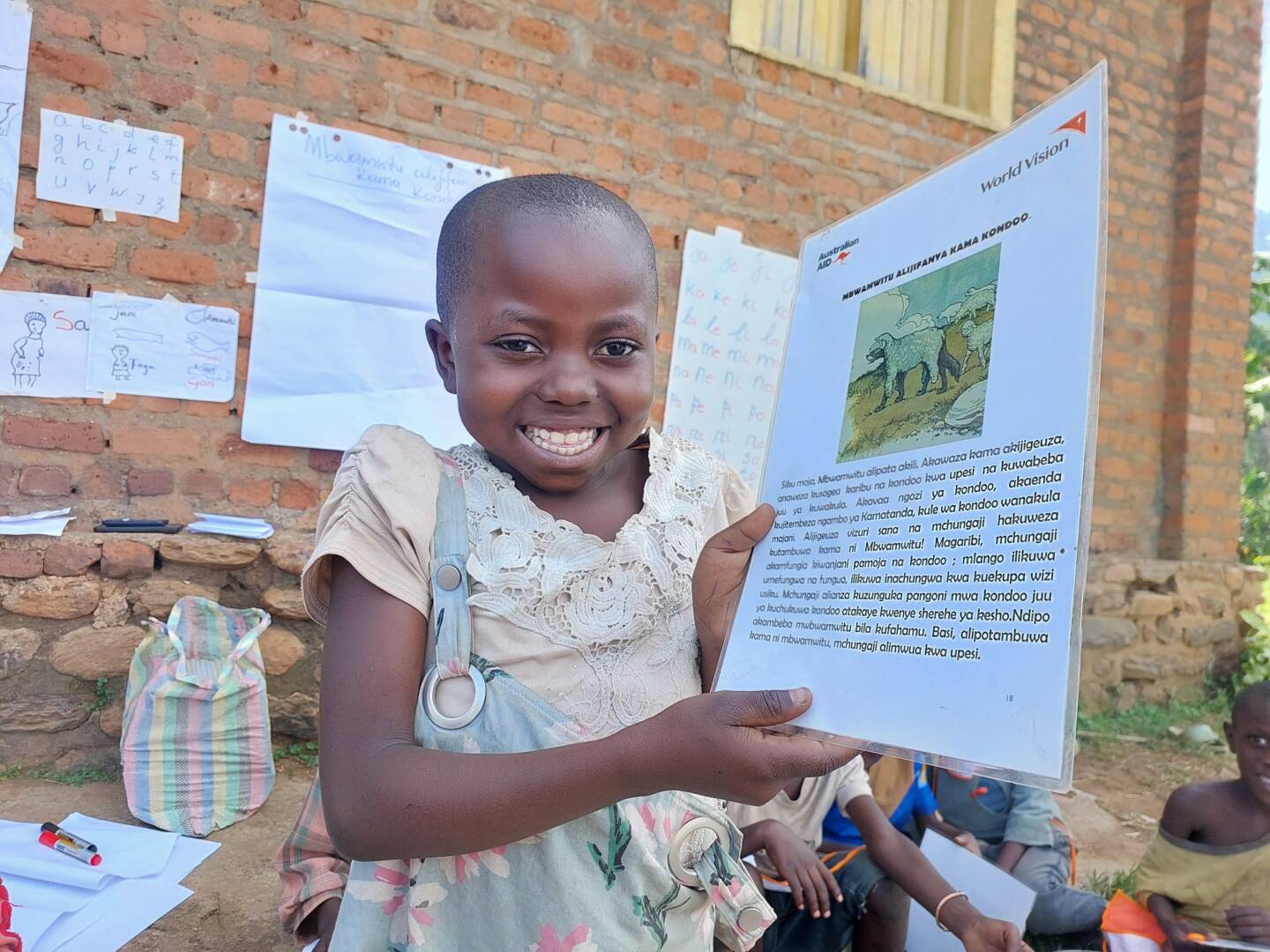 A girl with a big smile holds up a laminated paper.