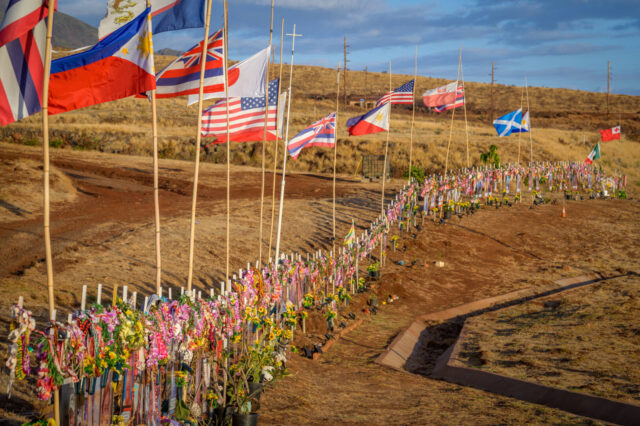 Flags from around the world are pitched in a memorial of crosses adorned with leis.