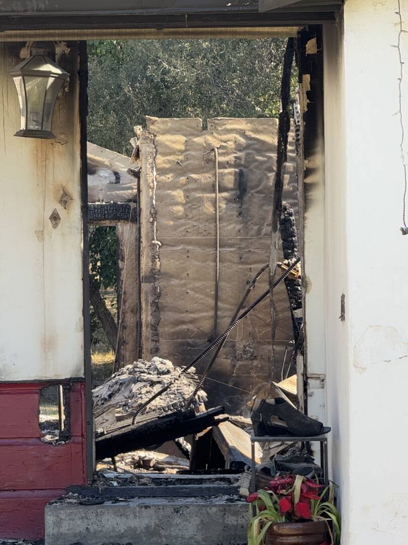 Shoes sit on a shoe rack outside a Pasadena home's front door. Through the doorframe, everything is burned down.