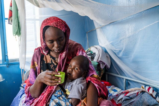 A mother holds her 2-year-old son at a stabilization clinic in Farchana, Chad. He was admitted with severe malnutrition.