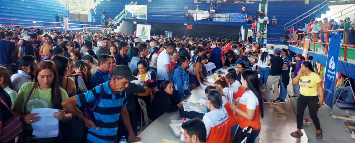 Inside a large stadium, a crowd gathers near aid distribution lines.