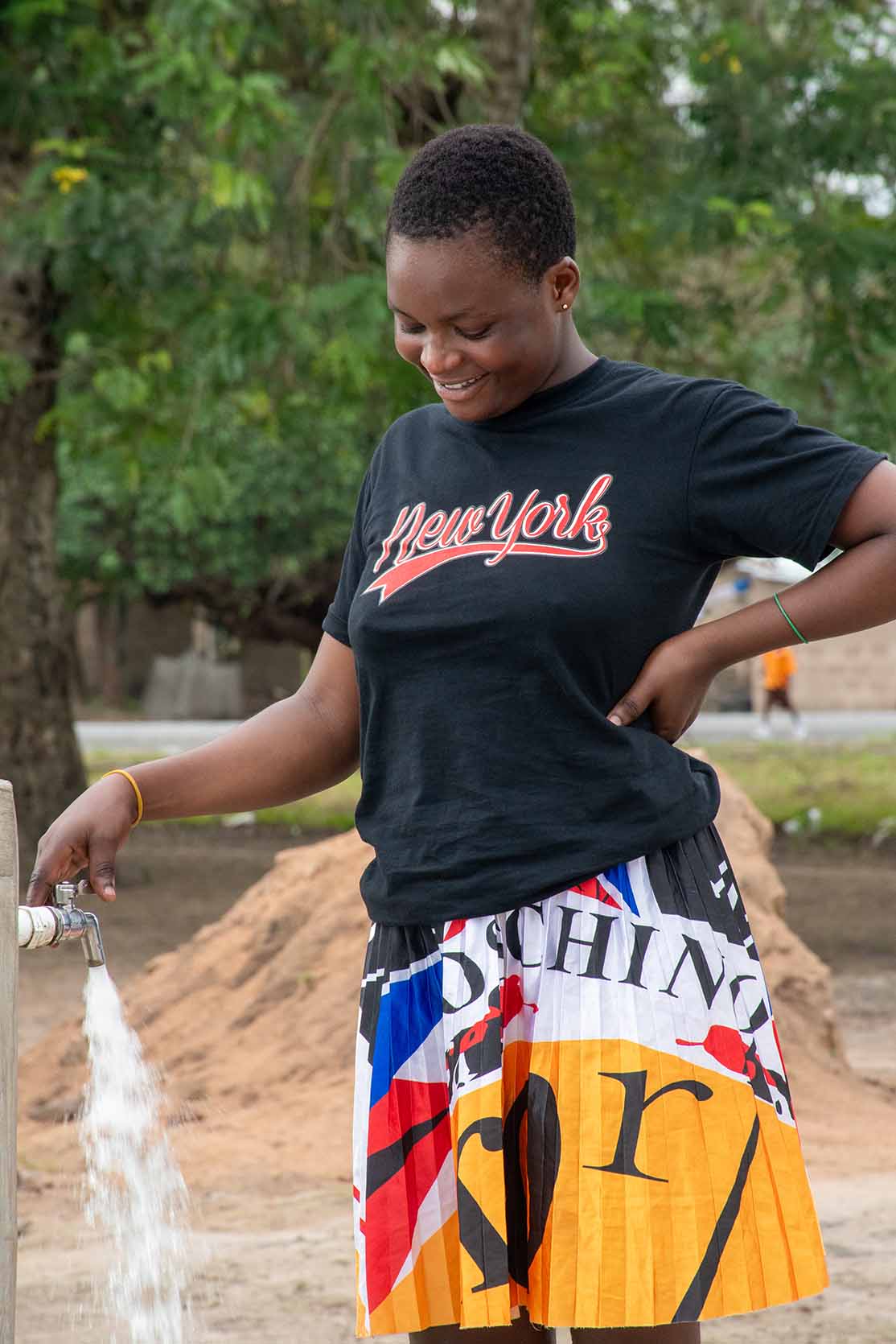 A young woman turns on the water tap and smiles as water pours out.