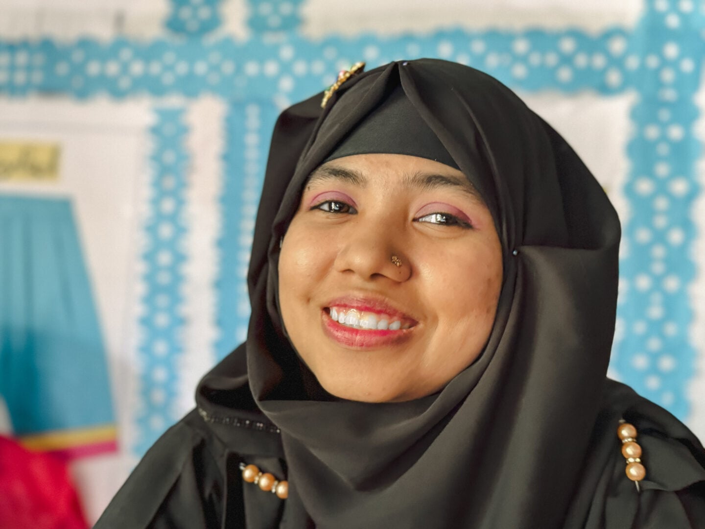 Portrait of a smiling young woman in a black headscarf.