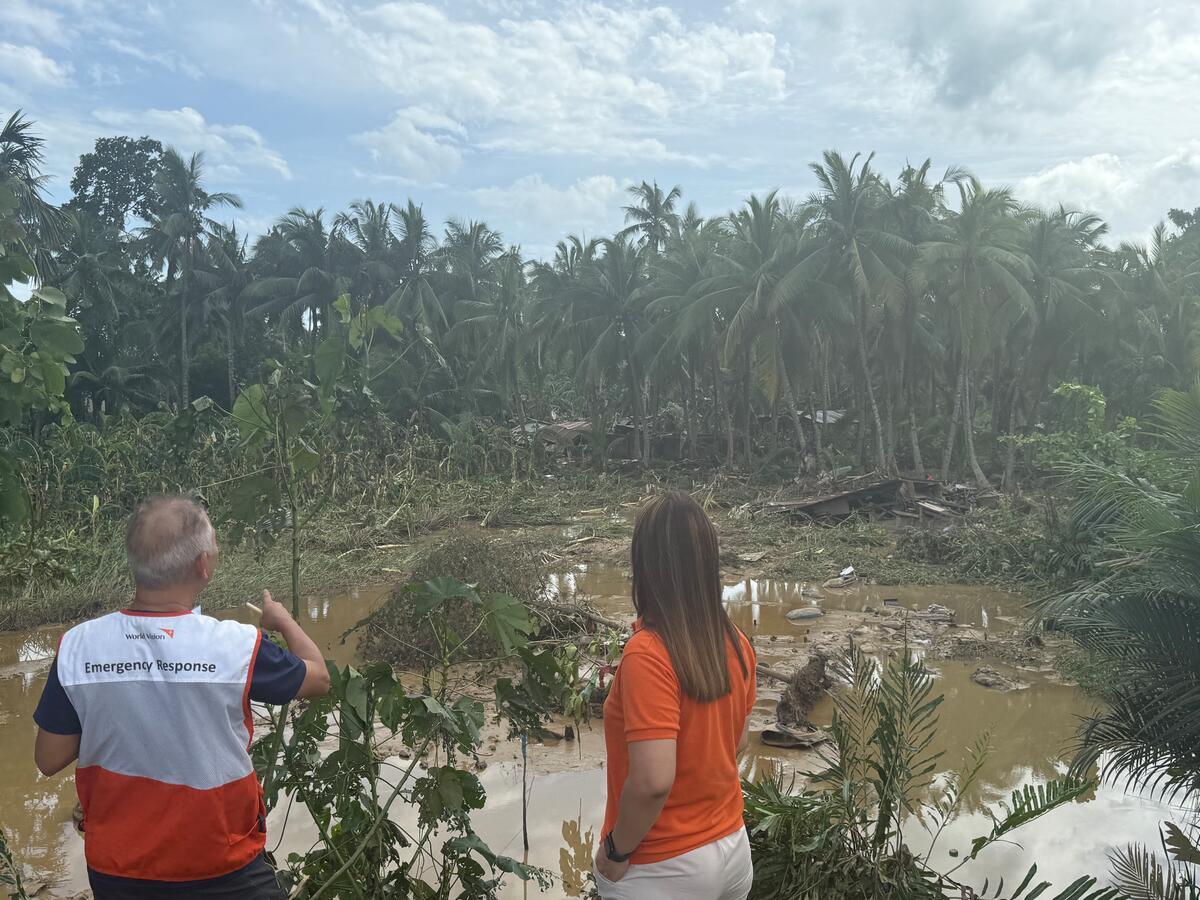 Aid workers survey a flooded landscape strewn with leveled palm streets in the Philippines.