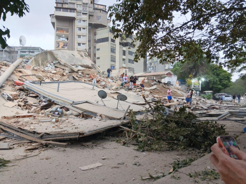 People stand on toppled buildings in Venezuela after earthquake.