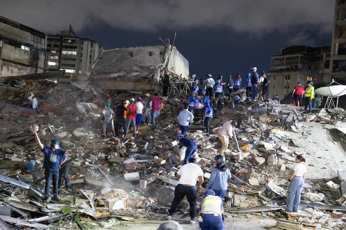 Lines of people stand piles of rubble and debris after the devastation of twin earthquakes in Venezuela.