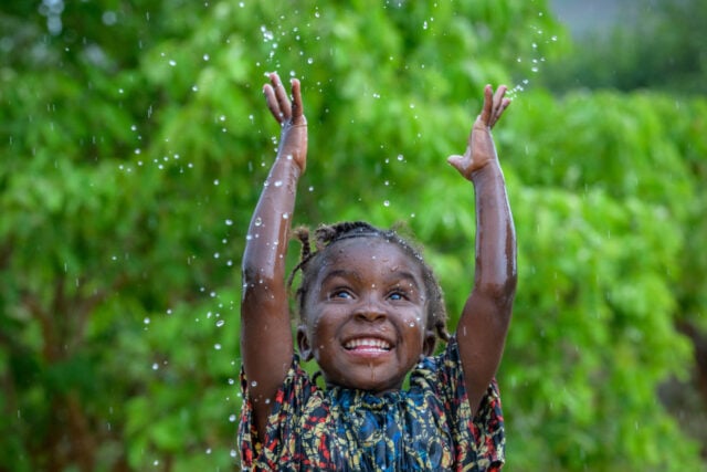 A little girl throws droplets of water into the air.