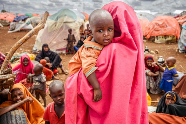 Children and their mothers, recently displaced IDP families, sit among their only possessions in Beco camp, Baidoa, Somalia. ©2023 World Vision