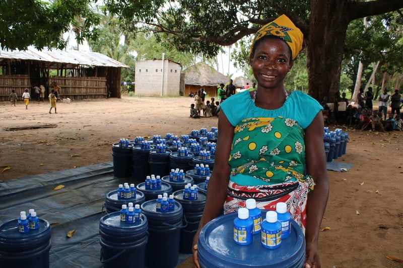 A smiling mother gratefully carries a package of donated hygiene supplies.