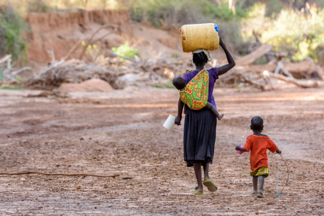 With her baby on her back and toddler by her side, a Kenyan mother walks in a dry riverbed in Kenya to dig for water at least twice a day, a distance of about 8 kilometers (4 miles). 6K is the average distance women and children in the developing world walk for water. Women and children in the developing world walk 200 million hours a day for water.