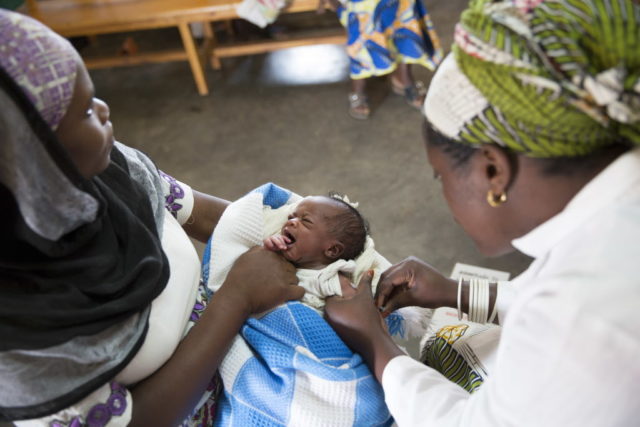 A medical staff member examines an infant at Kinihira Health Center in Rwanda. World Vision helped to provide health training and supplies for the center, which was built by the government. PHOTO: Lucy Aulich/World Vision
