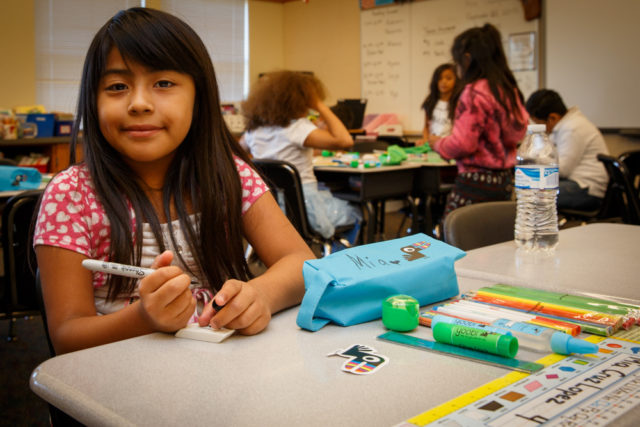 A girl smiles as she labels her new school supplies. World Vision and volunteers distributed Yoobi school supplies kits to students in Kent, Wash. (©2015 World Vision, Chris Huber)