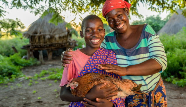 Resheal, holding a chicken, with his mother, Esnart. The chicken is an offspring of chickens his mother got through the Gift Catalog.