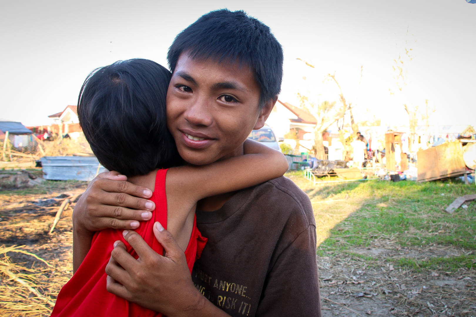 Standing near his home in the Philippines that was destroyed by Typhoon Haima in October 2016, Santiago holds his 4-year-old sister Princess. (©2016 World Vision, photo by Joy Malujo)