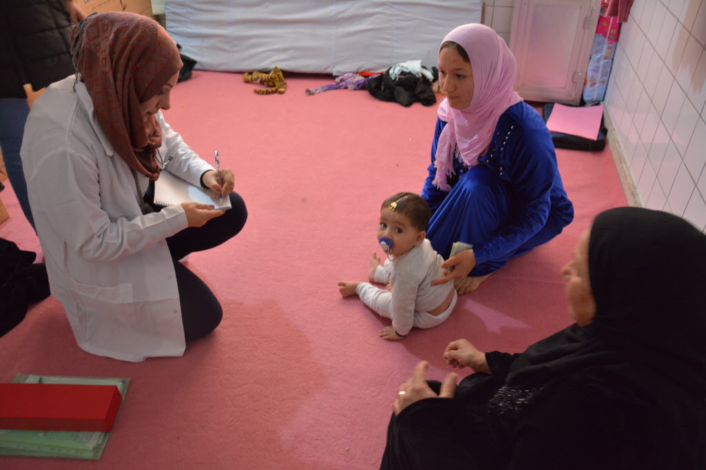 Dr. Maha talks to a mother and child during a visit to IDPs living in an abandoned hospital building. (©2015 Cecil Laguardia/World Vision)