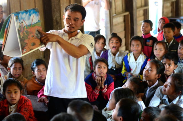 Phaytoun teaches school children about the dangers of aging bombs that are still found in the forest near his community in Laos. (©2015 World Vision, Mark Nonkes)