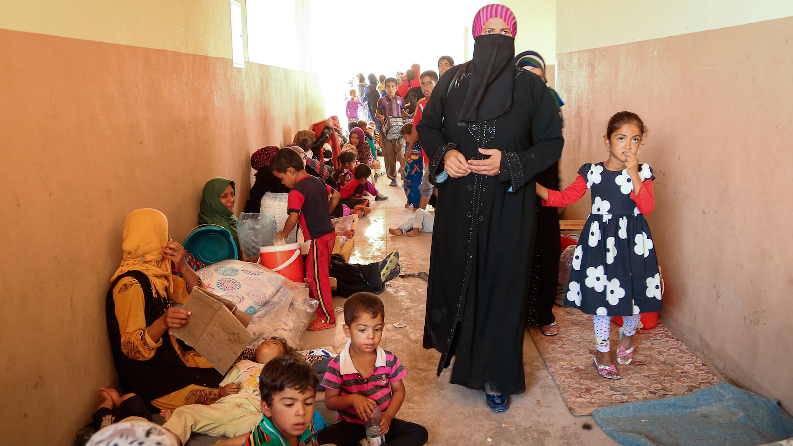 Iraq crisis: Hada and her daughter walk through the hall of a former school that serves as a transition center for women and children at Debaga camp in Iraq. (©2016 World Vision, Suzy Sainovski)