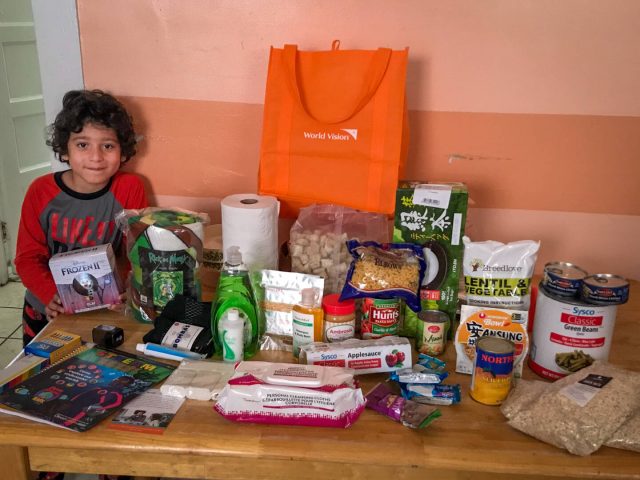 Six-year-old Ahni stands next to a table filled with supplies from World Vision Family Emergency Kits.